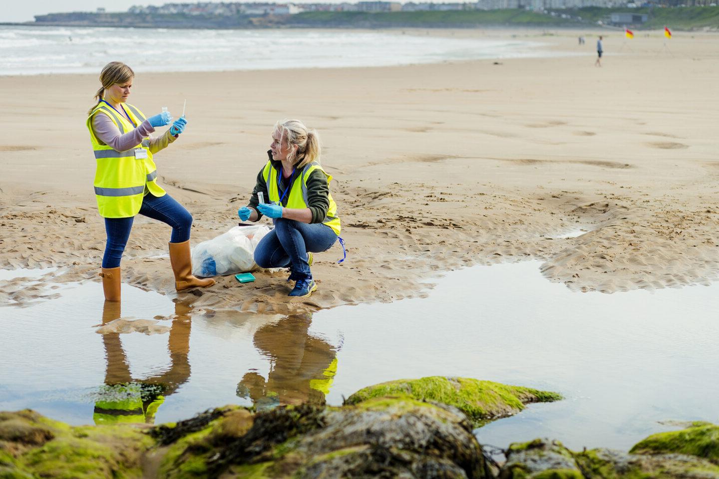 Two woman working near water taking samples