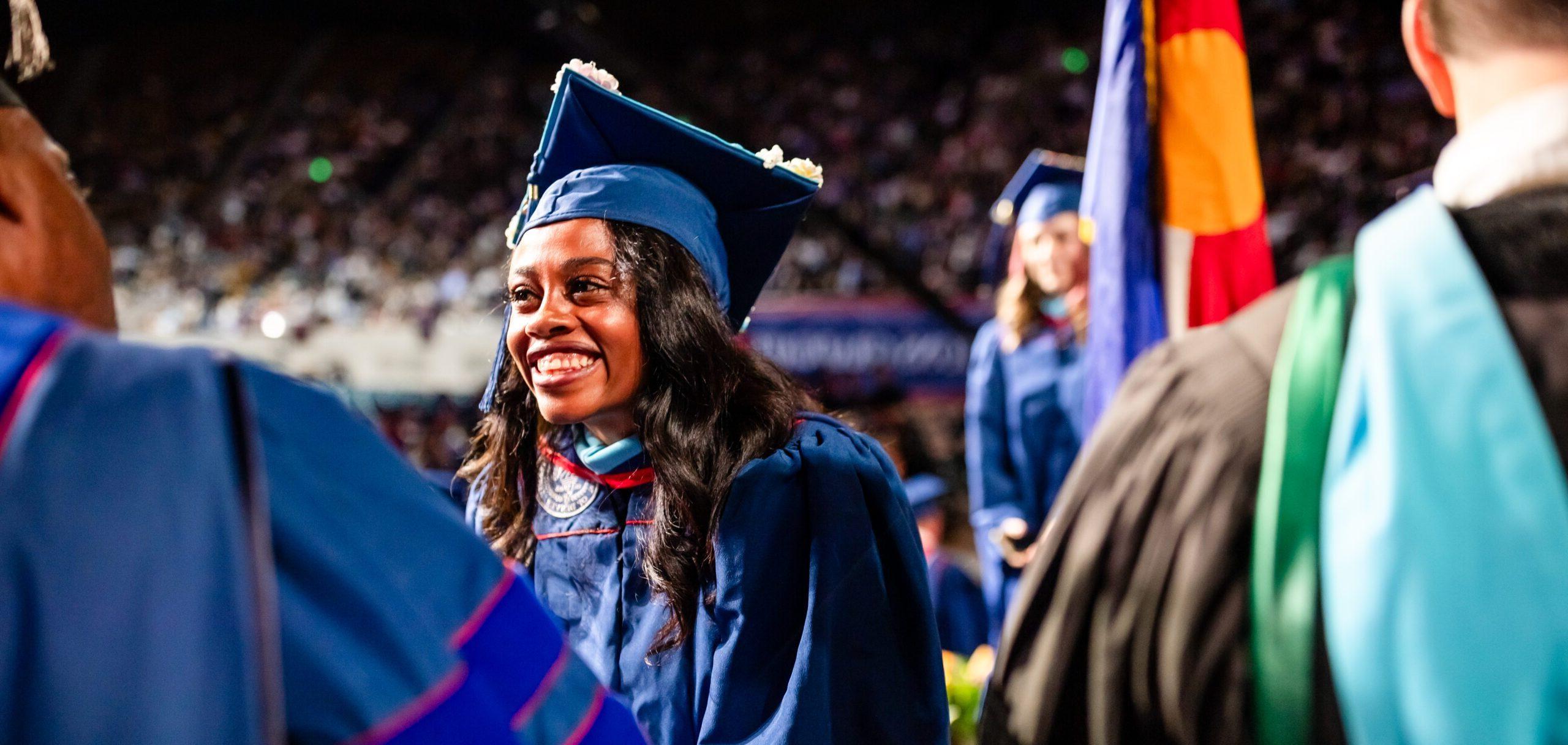 A graduate receives their diploma cover on stage at Commencement